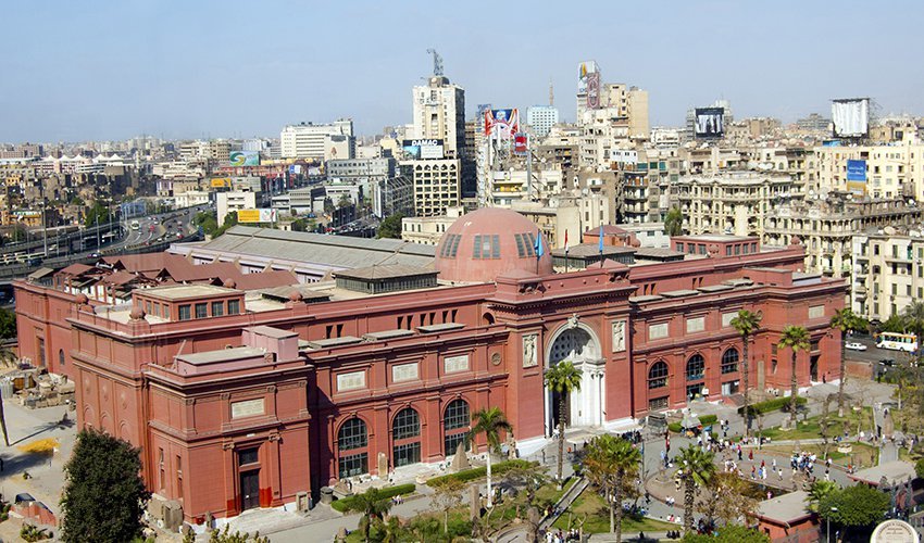 The Egyptian Museum in Tahrir Square, Cairo, with its iconic pink façade and historic architecture under a clear sky.